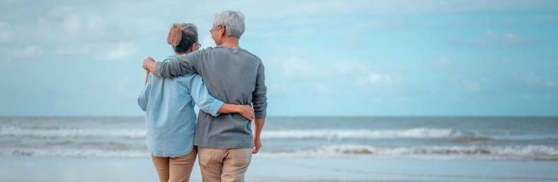 Man and woman walking on the beach discussing if a nursing home could take their home.